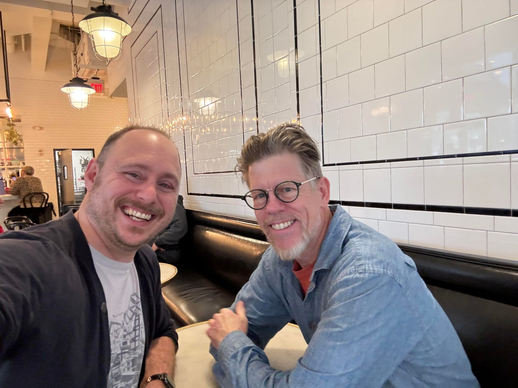 Nick Adams Pandolfo and Dylan Tweney, smiling at the camera while sitting in a cafe