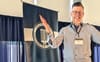 Dylan, smiling and gesturing, standing in front of a banner that says Professional Speechwriters Association