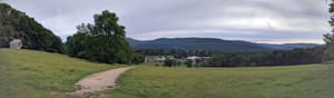 Trail panorama showing mountains, a distant village, and the "crystal" sculpture on the left.